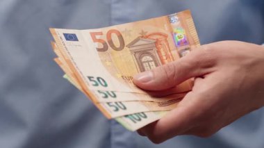 Avro banknotlarını tutan yakın plan erkek. Adam para verir. Tasarruf, gelecekteki zenginlik, yatırım veya kişisel finans için finansal konsept. Eğitim içeriği veya mali geçmiş için ideal. 