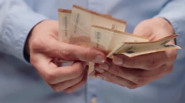 Avro banknotlarını sayan erkeklerin yakın çekimi. Mavi gömlekli adam para sayıyor, 50 Euro 'luk banknot. Maaş, tasarruf veya bütçe planlaması için mali konsept.