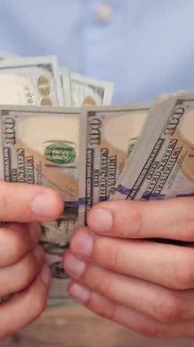 Adam yakın planda 100 Amerikan Doları 'nı sayıyor. Yatırım veya zenginlik geliştirme, mali planlama veya gelir için yatırımcı kavramı