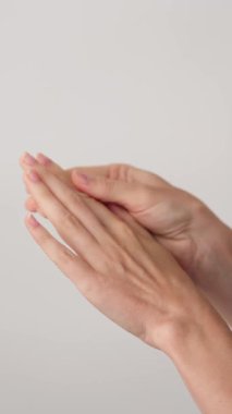 Zarif manikürlü, birbirine nazikçe masaj yapan kadın ellerinin dikey yakın çekimi. Rahatlama, özgüven ve güzellik. Güzellik Salonu Tanıtımı