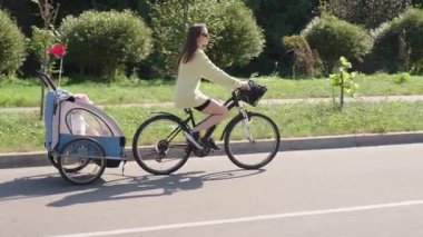 Güneşli bir günde bir çocuk karavanıyla bisiklet süren bir kadın açık havada eğleniyor. Anne ve çocuk bisiklete biniyor. Aile hayatı, çevre dostu ulaşım.