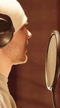 Gülümseyen Genç Adam, Mikrofona Konuşuyor, Kulaklıklar açık. Stüdyo Podcast 'i Yakalıyor. Modern Medya Yaratıcılığı, Dijital İletişim, Gençlik Kültürü, Yayın, Radyo Sunucusu