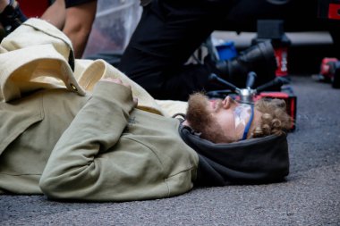 Londra, Birleşik Krallık, 21 Ağustos 2021 - Bir Yok Olma İsyanı protestocusu yolda yatarken, polis onu metal bir borudan kurtarmak için kesme ekipmanı kullandı