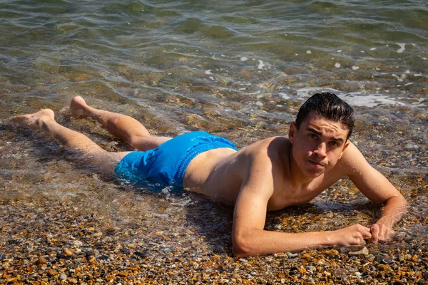 一名18岁的白种人少年赤身裸体躺在海浪中 — 图库照片