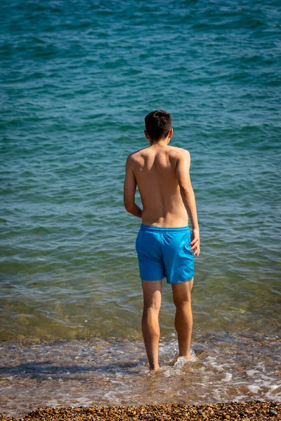 18歳の白人男の子で水着で海に歩いて — ストック写真