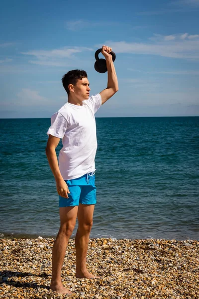 Egy Éves Kaukázusi Tinédzser Fiú Parton Gyakorol Egy Vízforraló Súllyal — Stock Fotó