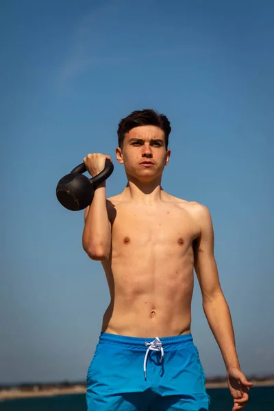 一名18岁的白种人少年 身穿泳衣 体重增加水壶重量 — 图库照片