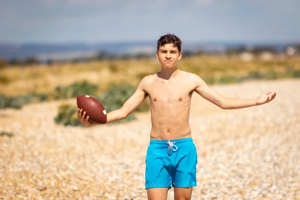 Letni Nastolatek Bez Koszuli Bawiący Się Plaży Futbolem Amerykańskim — Zdjęcie stockowe
