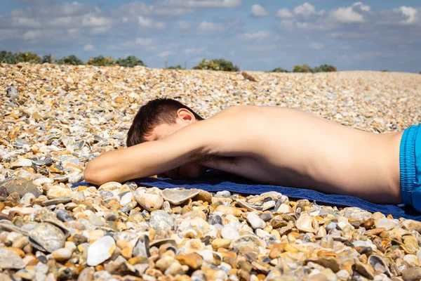 一名18岁的白种人少年赤身裸体在石头砸人的海滩上晒日光浴 — 图库照片