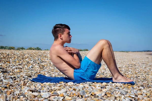 一名18岁的白种人少年赤身裸体坐在石滩上 — 图库照片