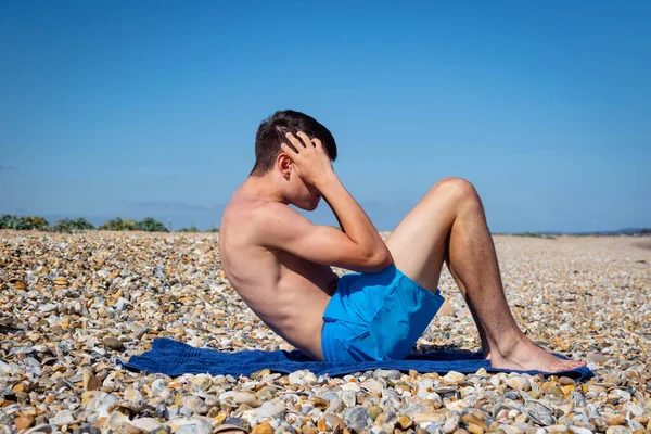 一名18岁的白种人少年赤身裸体坐在石滩上 — 图库照片