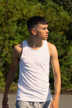 18 yaşında kolsuz tişörtlü bir genç yaz günü