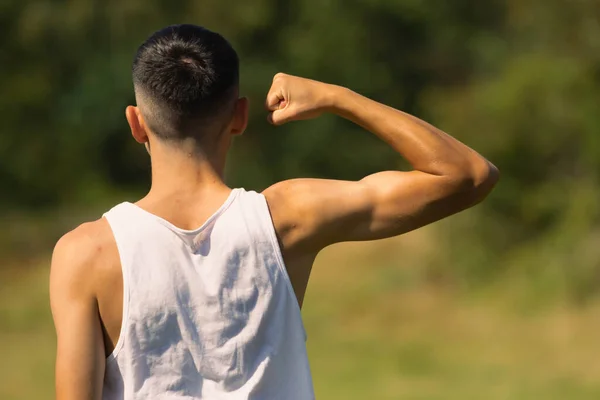 腕の筋肉を曲げ 夏の終わりに袖のない上に18歳の少年 — ストック写真