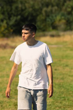 Beyaz tişörtlü ve şortlu 18 yaşında bir çocuk. 