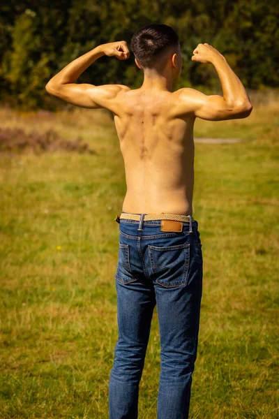 暖かい夏の日に公園で彼の筋肉を曲げ18歳の10代の少年 — ストック写真