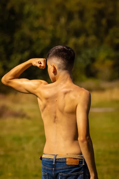 暖かい夏の日に公園で彼の筋肉を曲げ18歳の10代の少年 — ストック写真