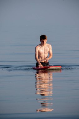 Teenage boy swimming in the sea with a body board on a warm summer's evening