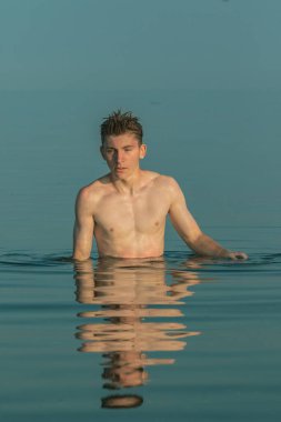 Teenage boy standing in the sea on a warm summer's evening