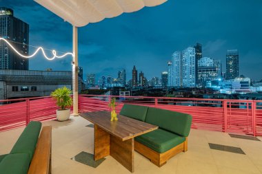 Alacakaranlıkta çağdaş çatı üstü barı ve şehir manzarası görünümü.