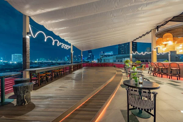 Alacakaranlıkta çağdaş çatı üstü barı ve şehir manzarası görünümü.