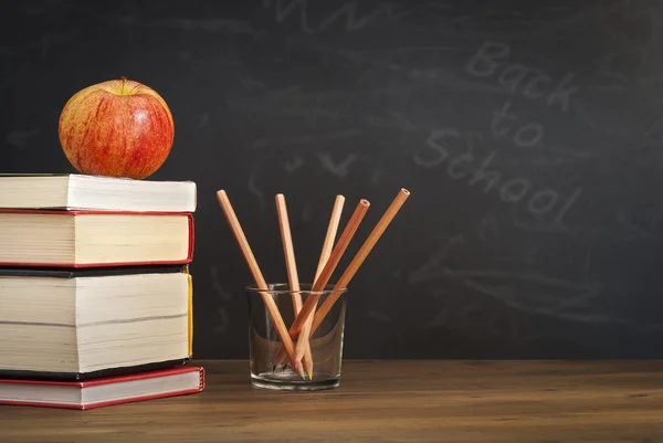 Apple på böcker med pennor och Tom blackboard - tillbaka till skolan — Stockfoto