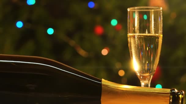 Πρωτοχρονιά Τηγάνι Από Ποτήρι Σαμπάνια Και Μπουκάλι Φόντο Χριστουγεννιάτικο Δέντρο — Αρχείο Βίντεο