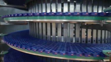 Otomatik eşya naklini gösteren bir fabrikadaki taşıma sistemi. Mavi kemerler, modern endüstriyel teknolojiyi eylem halinde gösteren metal raylar boyunca etkili bir şekilde hareket eder..