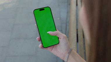 Kadın eli akıllı telefonun boş ekranına dokunuyor ve şehrin yakın planında uygulamayı açıyor. Şehirdeki mahsul manzarasında krom anahtar görüntüsü olan bir kadın cep telefonu tutuyor. Mobil uygulama reklamı