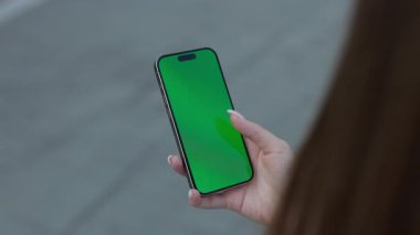 Kadın, şehir ortamında akıllı telefon yeşil krom anahtar ekranını elle dinliyor. Kadın, kentsel sokak ekin manzarasında model görüntülü cep telefonu kullanıyor. Şablon aygıtı tasarla