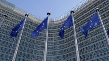 BRÜKSEL, BELGIUM - 27 Eylül 2025: AB 'nin mavi bayrakları Berlaymont' un ön cephesinde alçak açılı çekim yapan direklere doğru dalgalanıyor. Avrupa Komisyonu yönetim organları merkezi