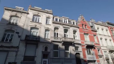BRÜKSEL, BELGIUM - 27 Eylül 2025: Avrupa şehrinin caddesinde ön cephelerinde klasik dekoru olan antik apartmanlar. Güneşli bir sabahta eski şehir evlerinin olduğu zarif bir mimari miras.