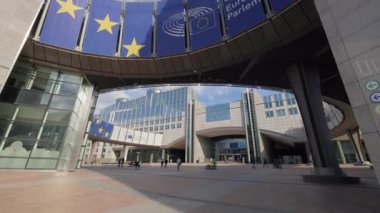 BRÜKSEL, BELGIUM - 27 Eylül 2025: İnsanlar Avrupa Parlamentosu binası girişinde mavi logotlu meydanda yürüyorlar. Turistler ve personel, iç avludaki hükümet binasını ziyaret etti