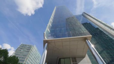 Modern The One ofis ve apartman binası şehrin düşük açılı çekimlerinde ergonomik cepheli. Gökyüzü altında bulutlarla sürdürülebilir mimari gelişim