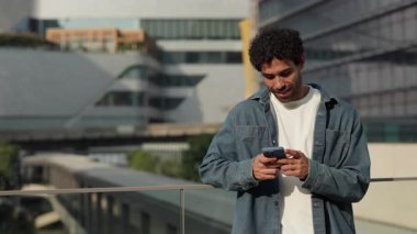 Düşünceli İspanyol adamın portresi şehir merkezindeki terasta duran akıllı telefondan mesaj yazıyor. Genç Latin erkek yaz kentinde sosyal medyada cep telefonuyla yazı yazıyor