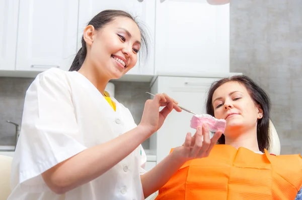 Стоматолог показує зубні протези пацієнту — стокове фото