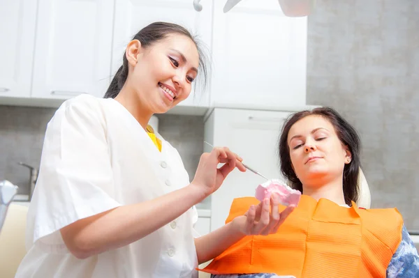 Стоматолог показує зубні протези пацієнту — стокове фото