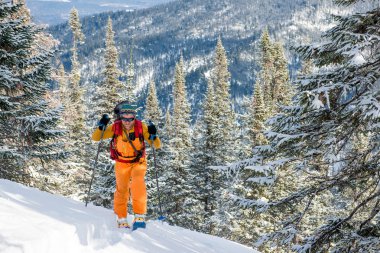 Dağın tepesinde yürüyen kayakçı.