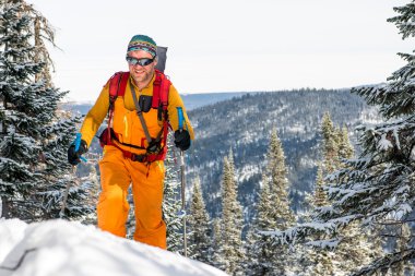 Dağın tepesinde yürüyen kayakçı.