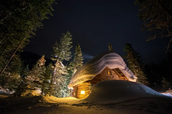 Деревянный коттедж в снежном лесу . — стоковое фото