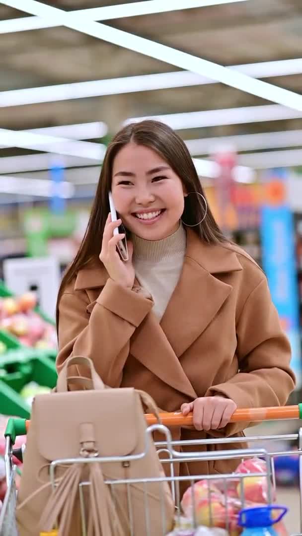 수직면의 젊은 여성이 감정적으로 전화하는 슈퍼마켓 — 비디오