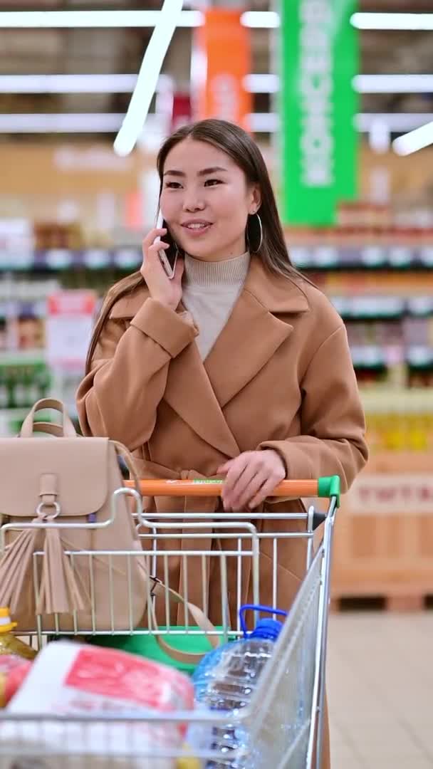 Покупець телефон говорити супермаркет вертикальний азіатський щасливий — стокове відео