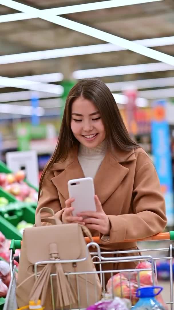 Aziatische vrouw chat telefoon internet supermarkt bestellen — Stockvideo