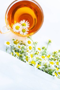 Beyaz arka plan doktoru tedavisi ve bağışıklık konsepti, ilaç - halk, alternatif, tamamlayıcı, geleneksel tıp üzerine bir fincan papatya çayı ve papatya çiçeği.