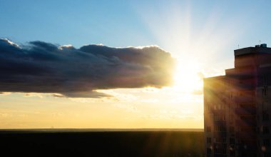 Bulutlar ve turuncu gün batımı, yüksek binaların yan manzarası. Gün batımı fırtınalı gökyüzü üzerinde inşaat alanı - grunge filtresi fotoğrafı