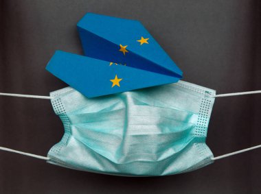 Avrupa Birliği bayrağındaki tıbbi yüz maskesi antiseptik ve kağıt uçak - Coronavirus salgını sırasında yurtdışına seyahat kavramı, yeni uçuş yasağı seyahat, havacılık işi