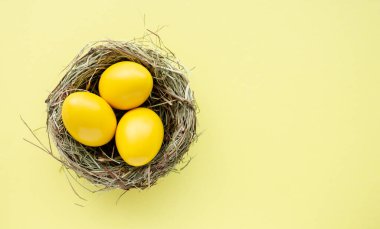 Mutlu Paskalyalar. Yuva görünümlü arka planda renkli sarı Paskalya yumurtaları, seçici odak resmi