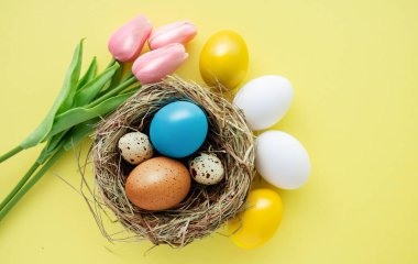 Mutlu Paskalyalar. Yuva görünümlü arka planda renkli sarı Paskalya yumurtaları, seçici odak resmi