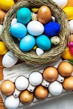 Mutlu Paskalyalar. # Renkli mavi, bej, beyaz Paskalya yumurtaları # # Yuva manzarasında # # Ahşap arka planda bahar çiçekleri, seçici odak görüntüsü #.