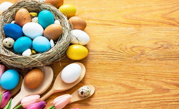 Mutlu Paskalyalar. # Renkli mavi, bej, beyaz Paskalya yumurtaları # # Yuva manzarasında # # Ahşap arka planda bahar çiçekleri, seçici odak görüntüsü #.