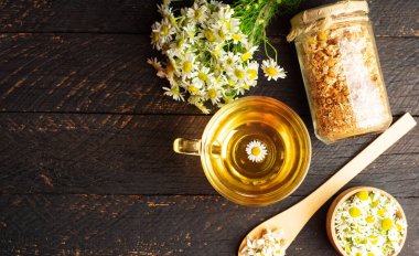 Rahatlatıcı bir fincan papatya çayı ve taze papatya çiçekleri.